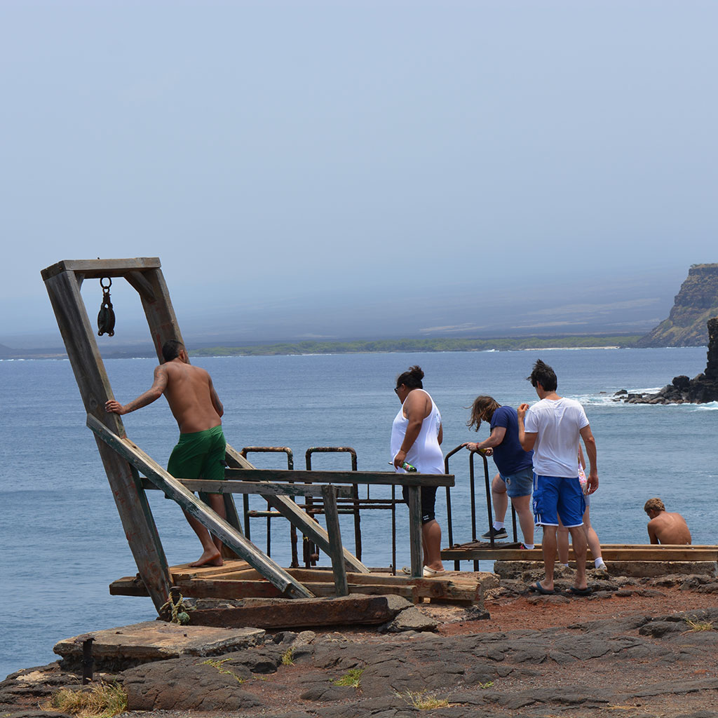 People jumping off the cliff at South Point - a must visit place during your Big Island driving tours