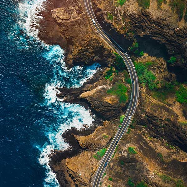 aerial view of a rod in between a mountain and the sea