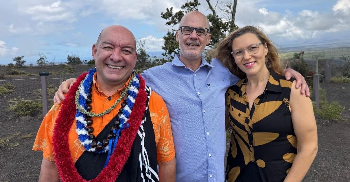 Three people smiling and standing together at Hawai‘i Volcanoes National Park during a wedding, embracing the Aloha spirit.